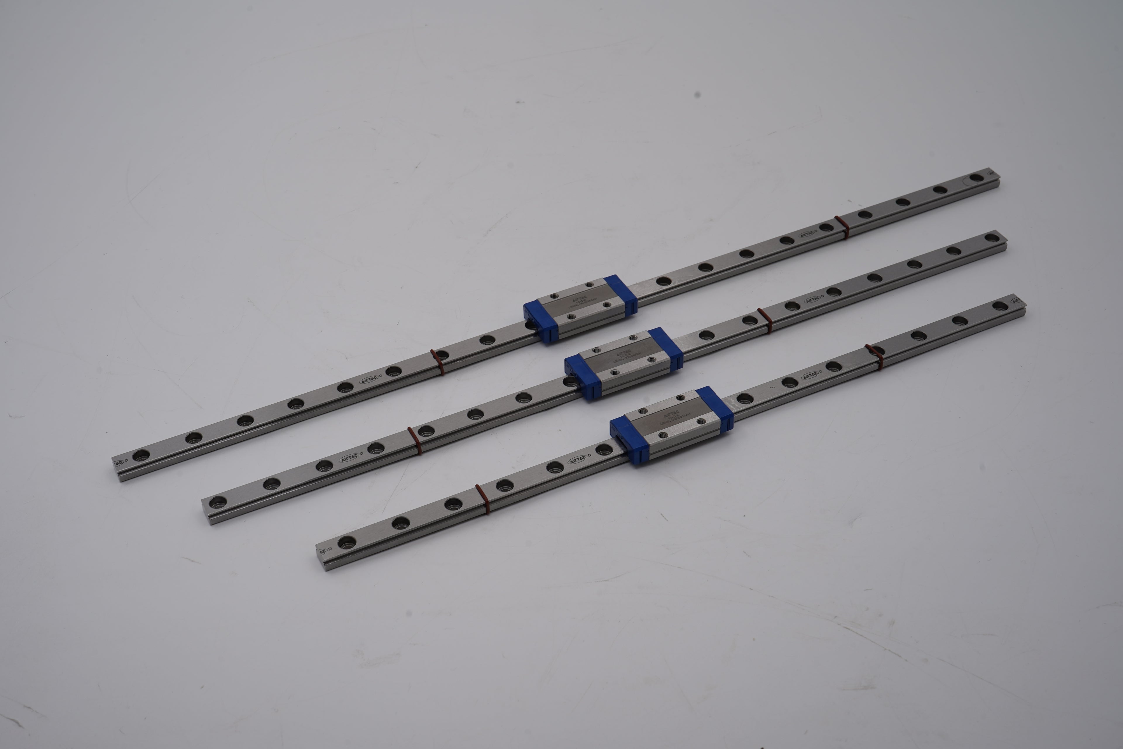 Three metal linear guides with bearings on a white background